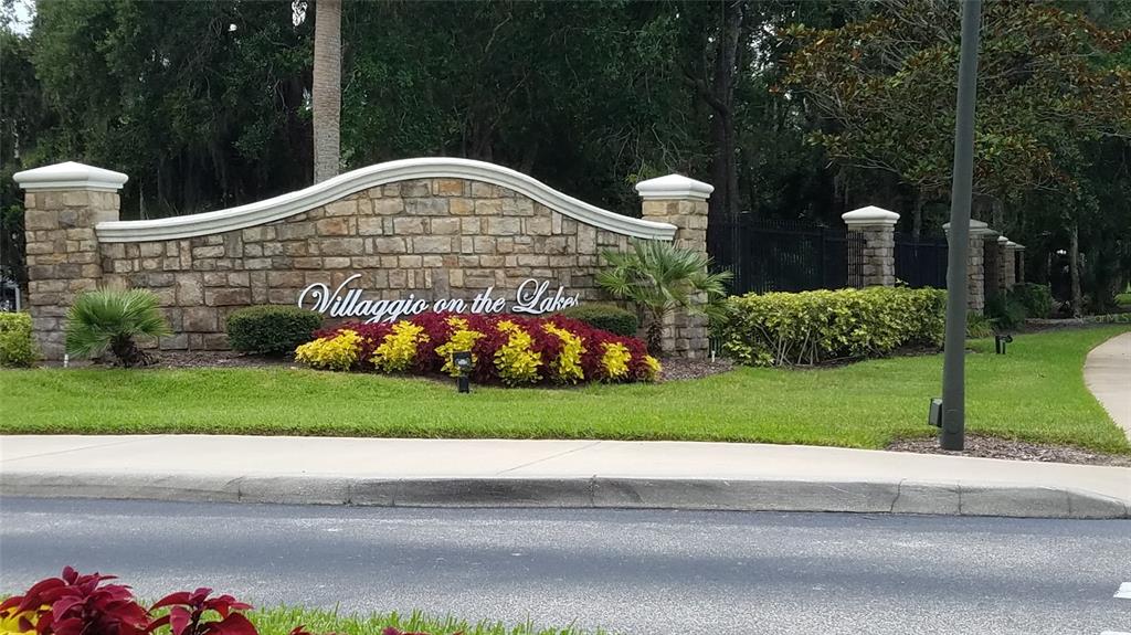 A stone monument sign for Villaggio on the Lakes stands behind a landscaped garden bed — 940 VILLAGE TRAIL UNIT 3-205, PORT ORANGE, FL