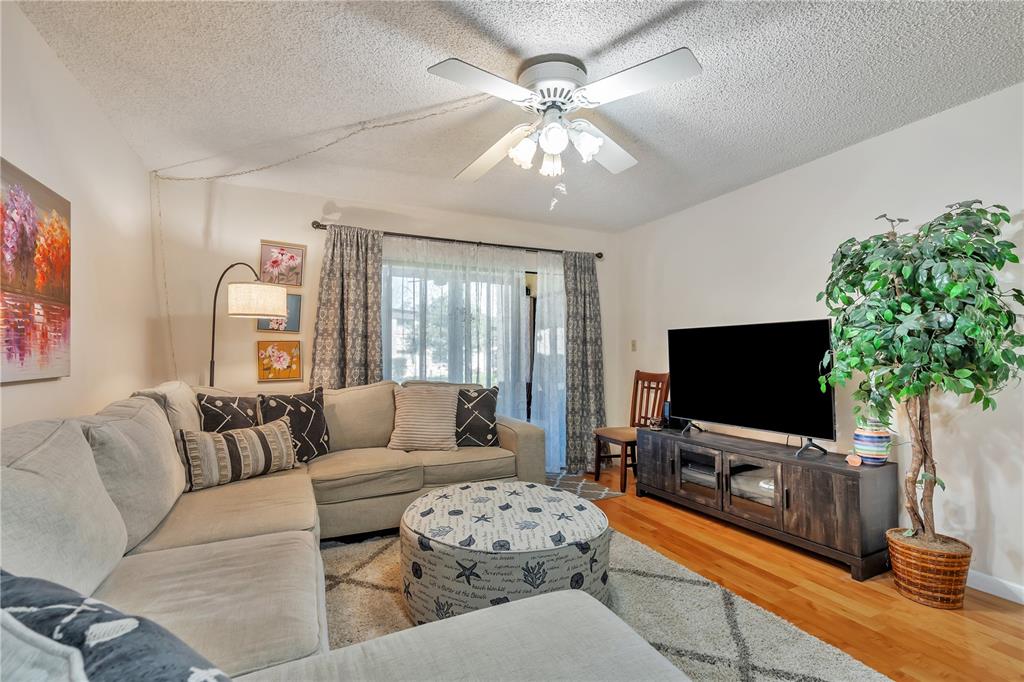A living room features a sectional sofa, a patterned ottoman, a television, and a ceiling fan — 2400 WINDING CREEK BOULEVARD UNIT 24-102, CLEARWATER, FL