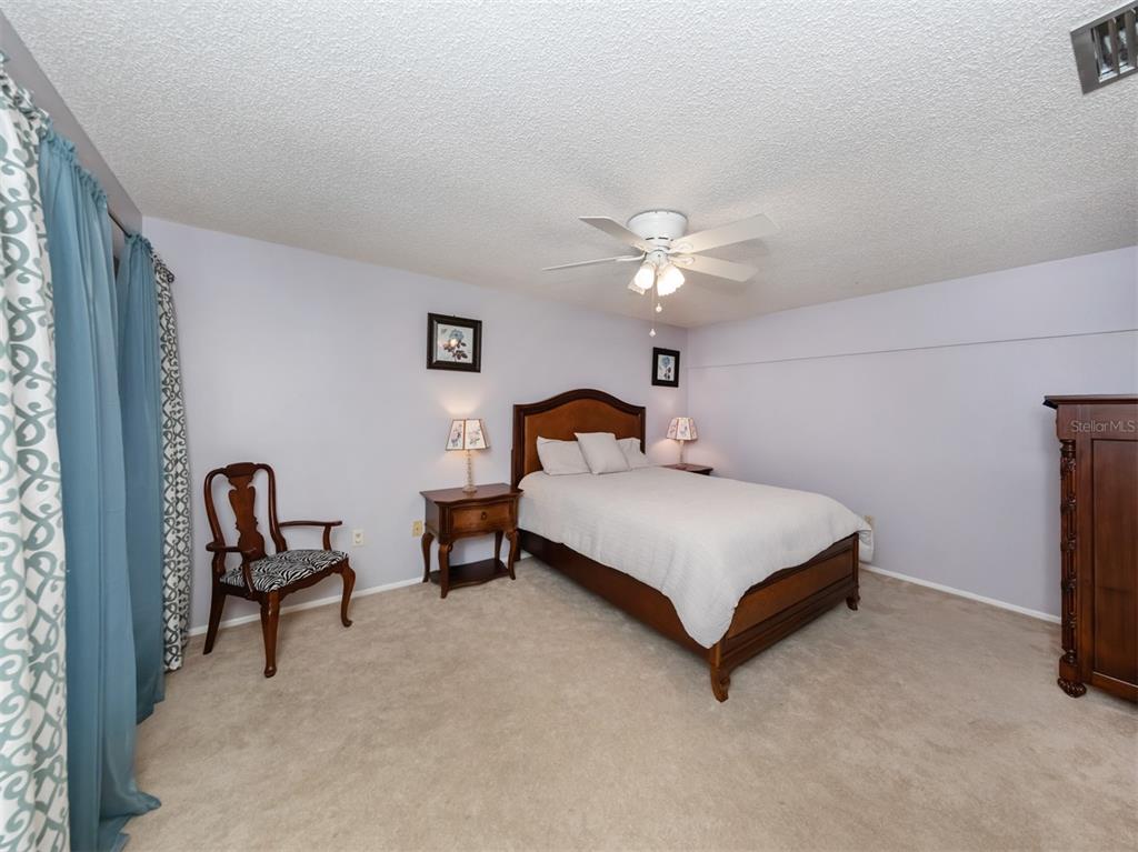 A bedroom features a wooden bed frame, two nightstands, a chair, and blue patterned curtains — 3222 GOLDEN EAGLE LANE, SARASOTA, FL