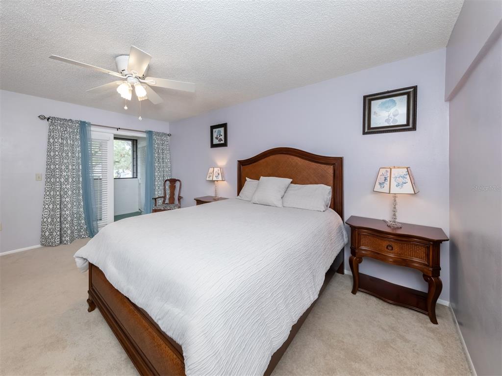 A bedroom features a wooden bed frame, two nightstands with lamps, and a sliding glass door — 3222 GOLDEN EAGLE LANE, SARASOTA, FL