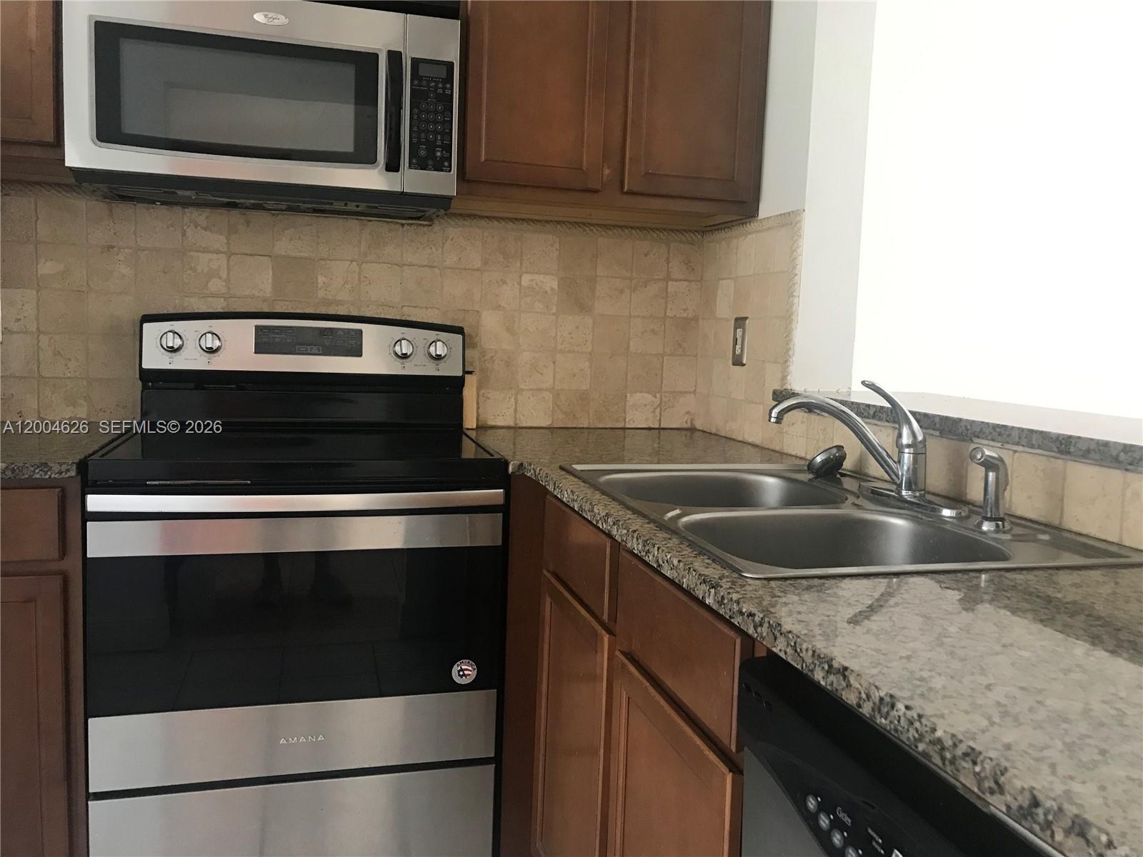 A kitchen features stainless steel appliances, wood cabinets, granite countertops, and a tiled backsplash — 3825 NW 90th Ave # 3825, Sunrise FL 33351, SUNRISE, FL