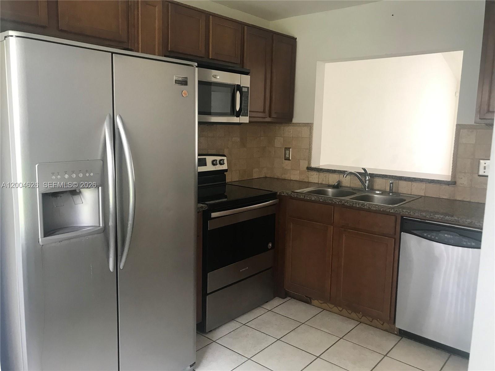 A kitchen features stainless steel appliances, dark wood cabinets, granite countertops, and tiled flooring — 3825 NW 90th Ave # 3825, Sunrise FL 33351, SUNRISE, FL