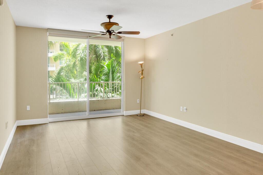 An empty room with light wood floors, beige walls, a ceiling fan, and sliding glass doors — 700 E Boynton Beach Boulevard # 407, Boynton Beach FL 33435, BOYNTON BEACH, FL
