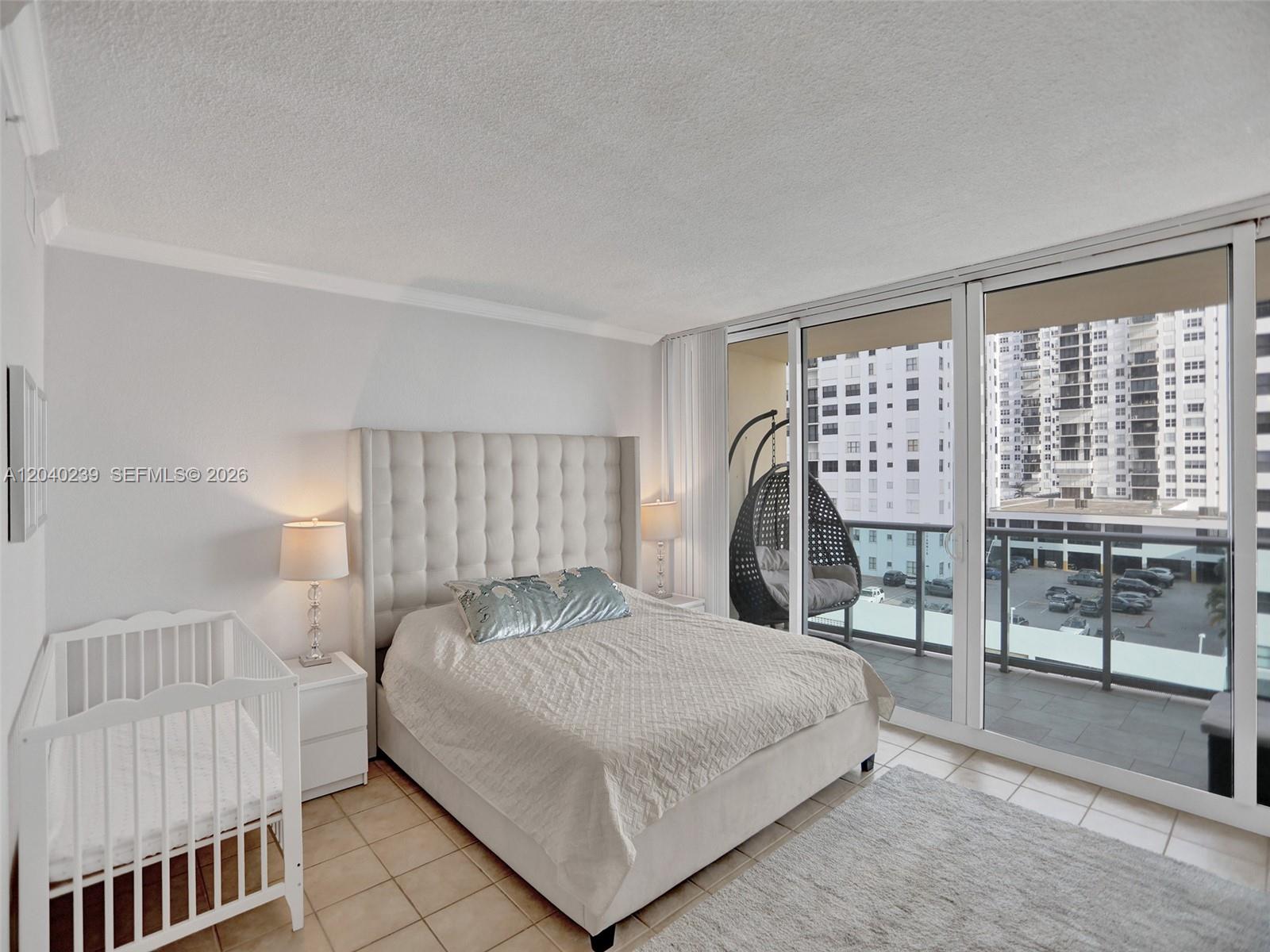 A bedroom features a tufted headboard, a white crib, and a balcony with a hanging chair — 2501 S Ocean Dr, Hollywood FL 33019, HOLLYWOOD, FL