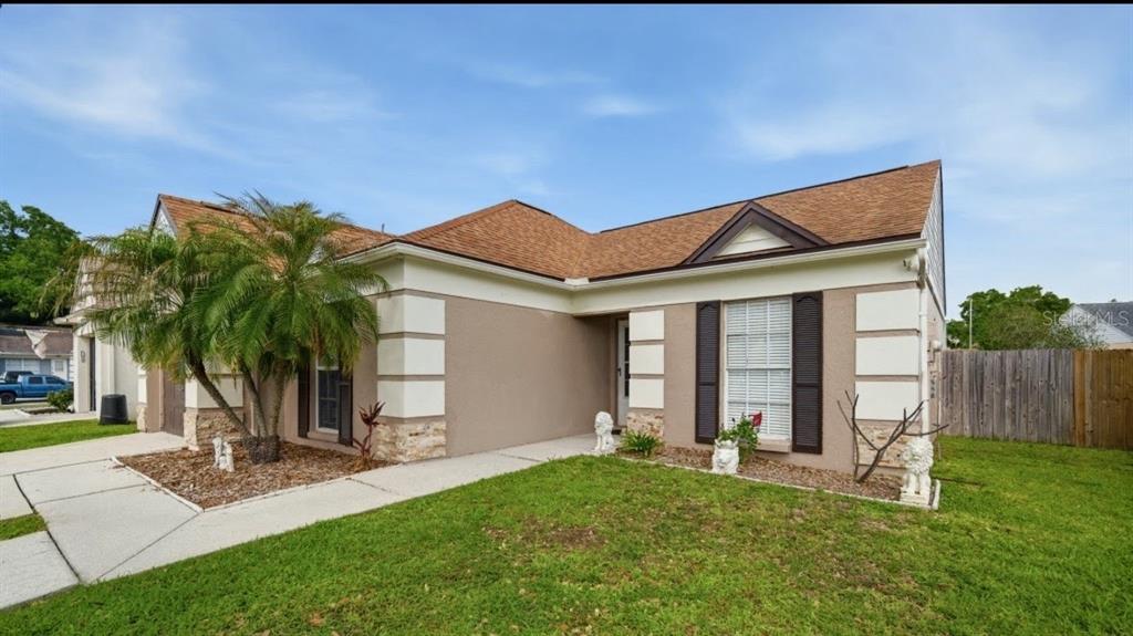 A single-story house with a tan stucco exterior, brown roof, and a front lawn — 2115 SHADY POINT LANE, BRANDON, FL