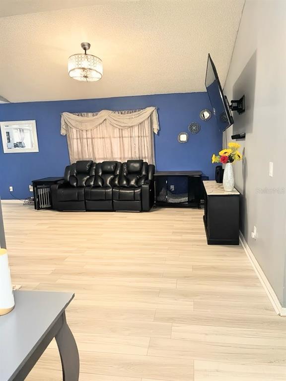 A living room features light wood-look flooring, a blue accent wall, and a black sofa — 2115 SHADY POINT LANE, BRANDON, FL