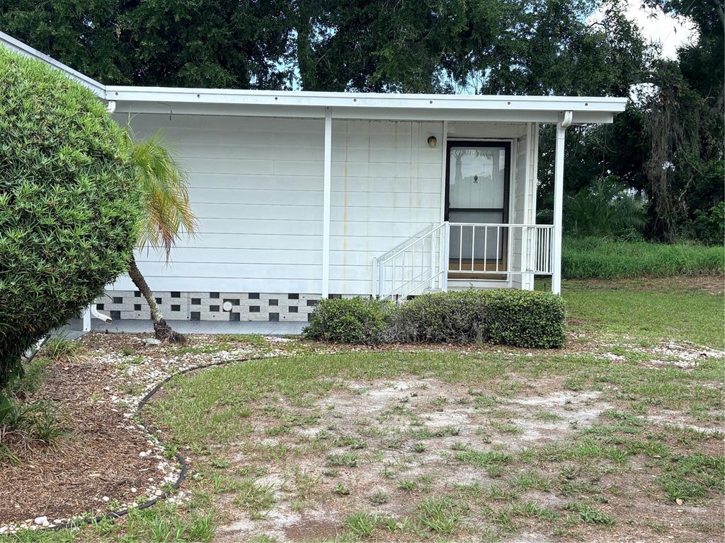 The exterior of a white mobile home features a small porch, stairs, and landscaping — 8519 BUCKINGHAM PLACE, PALMETTO, FL