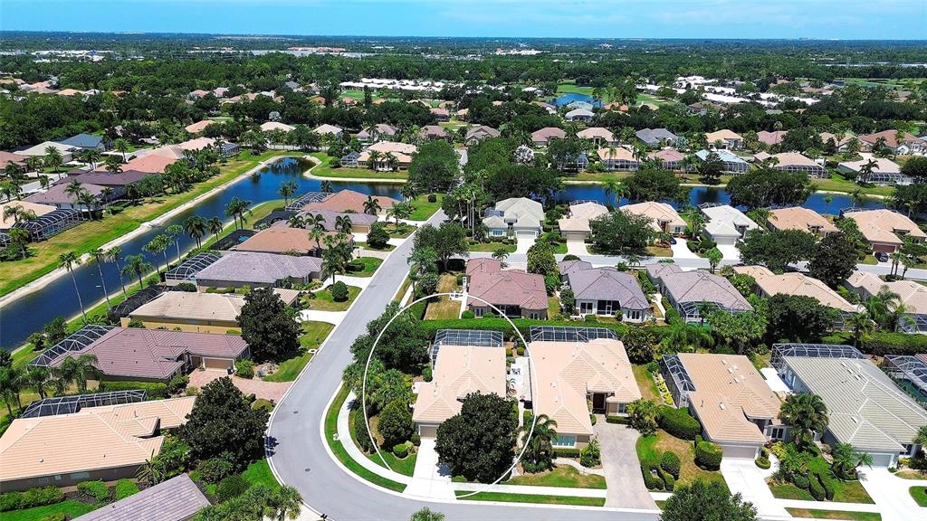 An aerial view shows a residential neighborhood with houses, a canal, and a circled property — 9735 53RD DR E, BRADENTON, FL