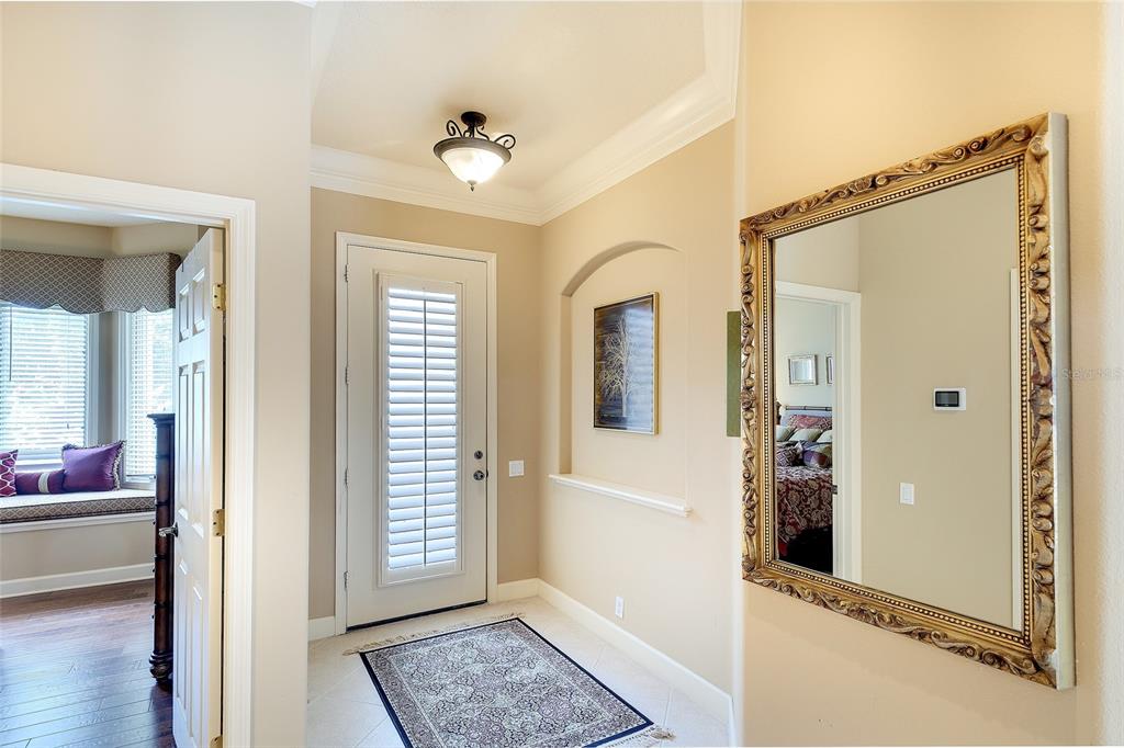 A foyer features a white door with shutters, a decorative mirror, and a tiled floor — 9735 53RD DR E, BRADENTON, FL