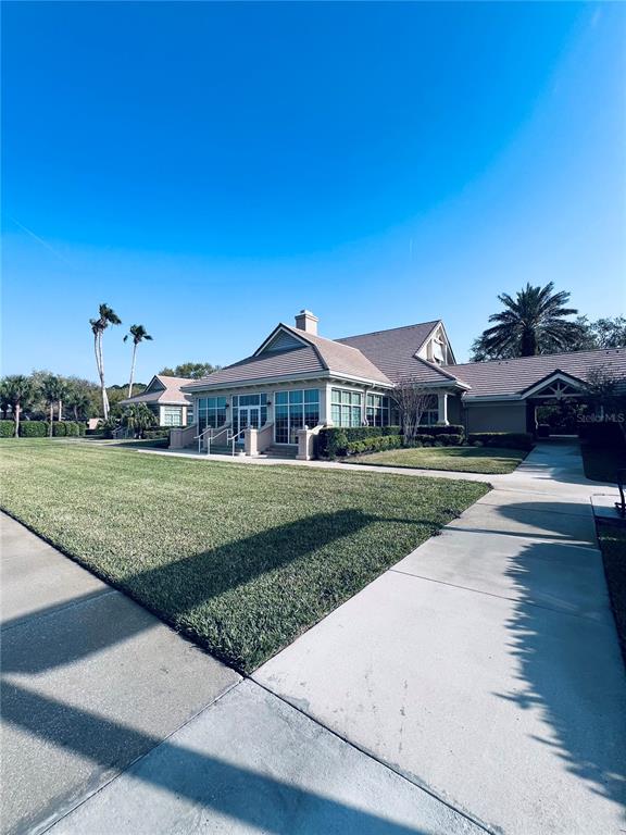 A low-angle exterior view of a community clubhouse with a large lawn and sidewalk — 91 EMERALD LAKE DRIVE, PALM COAST, FL