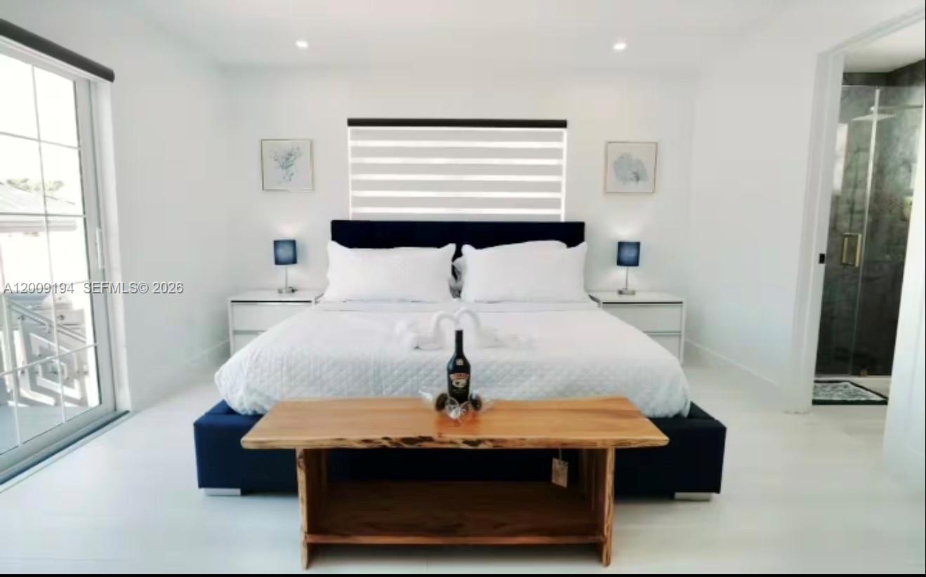 A modern bedroom features a dark blue bed, a wooden bench, and white walls — 2133 Yellowtail Dr, Marathon FL 33050, MARATHON, FL