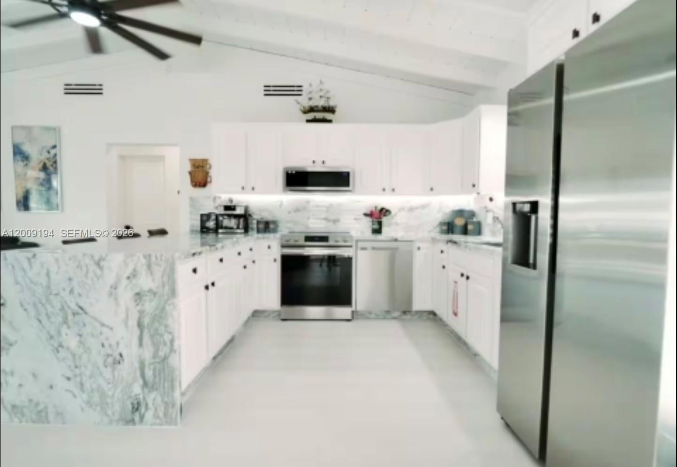 A kitchen features white cabinetry, stainless steel appliances, and a marble-patterned peninsula countertop — 2133 Yellowtail Dr, Marathon FL 33050, MARATHON, FL
