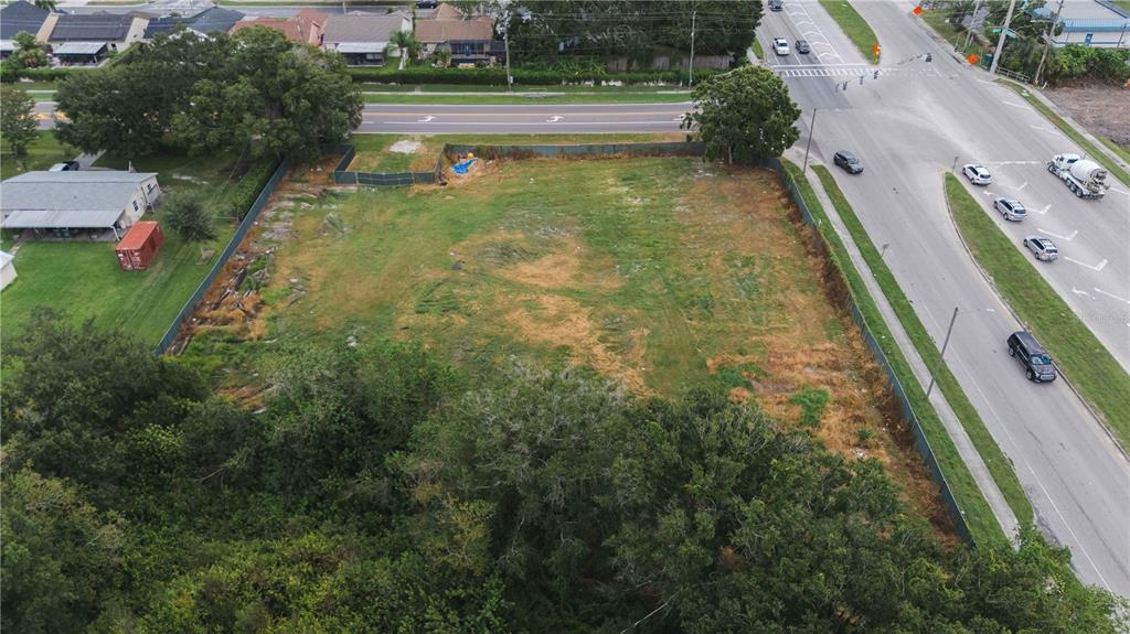 An aerial view shows a vacant, fenced-in grassy lot situated between two roads — 5406 W LINEBAUGH AVENUE, TAMPA, FL