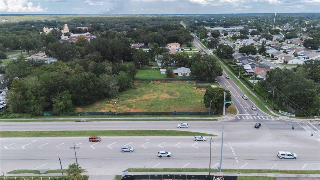 An aerial view shows a vacant, fenced-in lot situated next to a multi-lane road — 5406 W LINEBAUGH AVENUE, TAMPA, FL