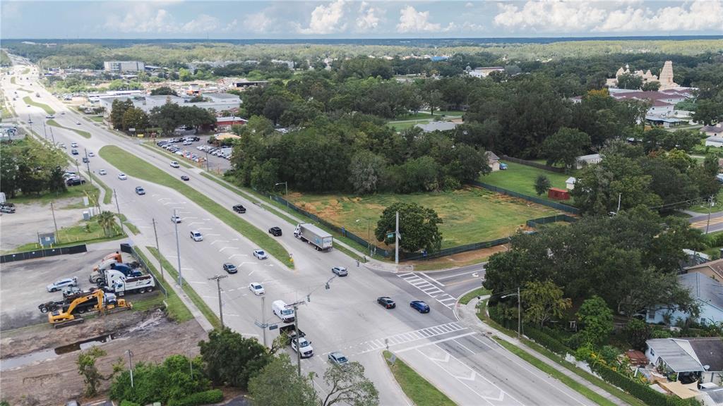 An aerial view shows a vacant lot situated at a busy intersection with nearby commercial buildings — 5406 W LINEBAUGH AVENUE, TAMPA, FL
