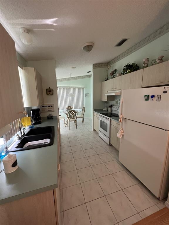 A kitchen with light wood cabinets, a white refrigerator, and a tiled floor — 1232 ZAPATA PLACE, LADY LAKE, FL