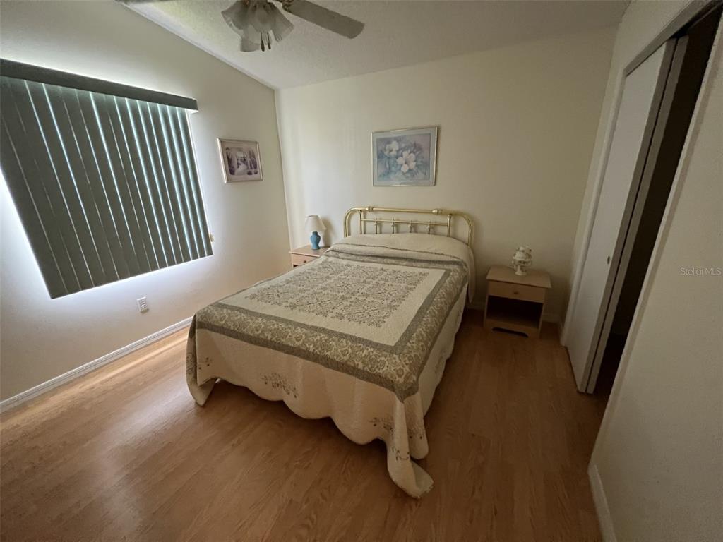 A bedroom features a bed with a gold metal frame, light wood flooring, and blinds — 1232 ZAPATA PLACE, LADY LAKE, FL