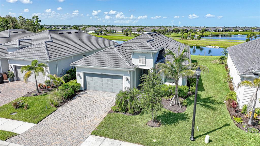 An aerial view shows a suburban house with a gray tile roof and paver driveway — 15039 BLACK CHERRY WAY, PUNTA GORDA, FL
