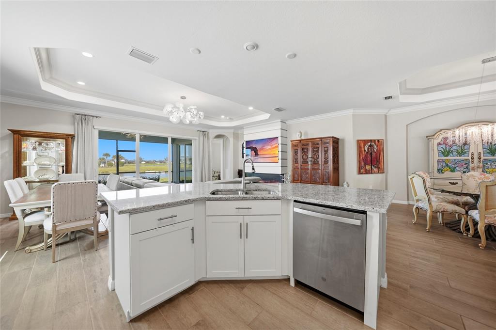A kitchen island with a stainless steel dishwasher sits in an open-concept living area — 15039 BLACK CHERRY WAY, PUNTA GORDA, FL
