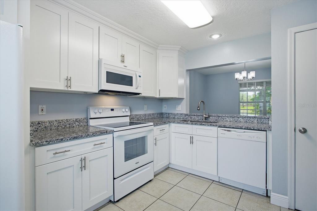 A kitchen features white cabinets, granite countertops, a white stove, and a white dishwasher — 2321 WATER VIEW LOOP, KISSIMMEE, FL
