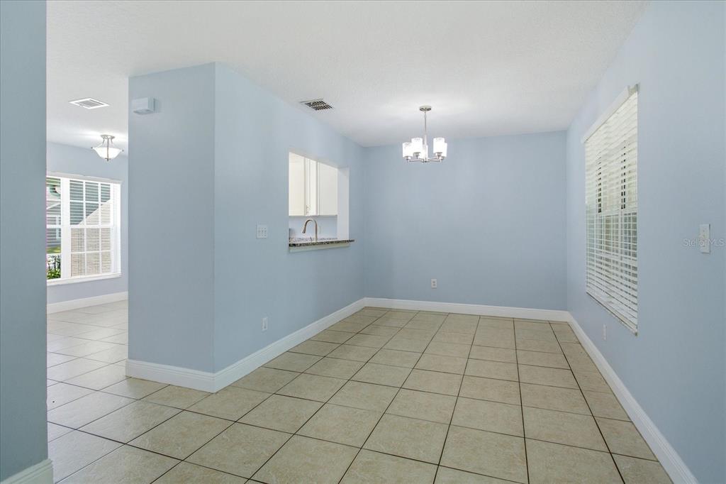 A dining area with light blue walls, tile flooring, a chandelier, and a kitchen pass-through — 2321 WATER VIEW LOOP, KISSIMMEE, FL