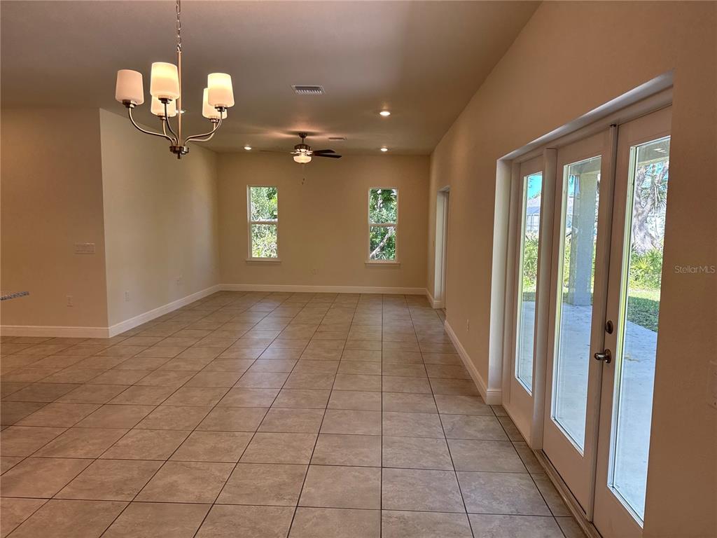 An empty room with tiled floors, a chandelier, and glass doors leading to a patio — 4698 ADDLEY AVENUE, NORTH PORT, FL