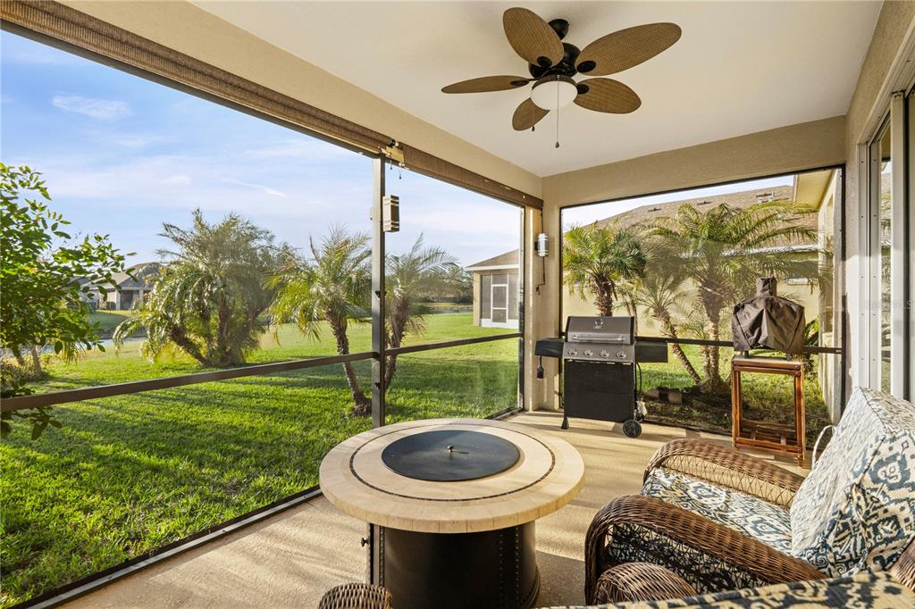 A screened-in patio features a fire pit, a grill, wicker furniture, and a view of grass — 12807 24TH STREET CIRCLE E, PARRISH, FL