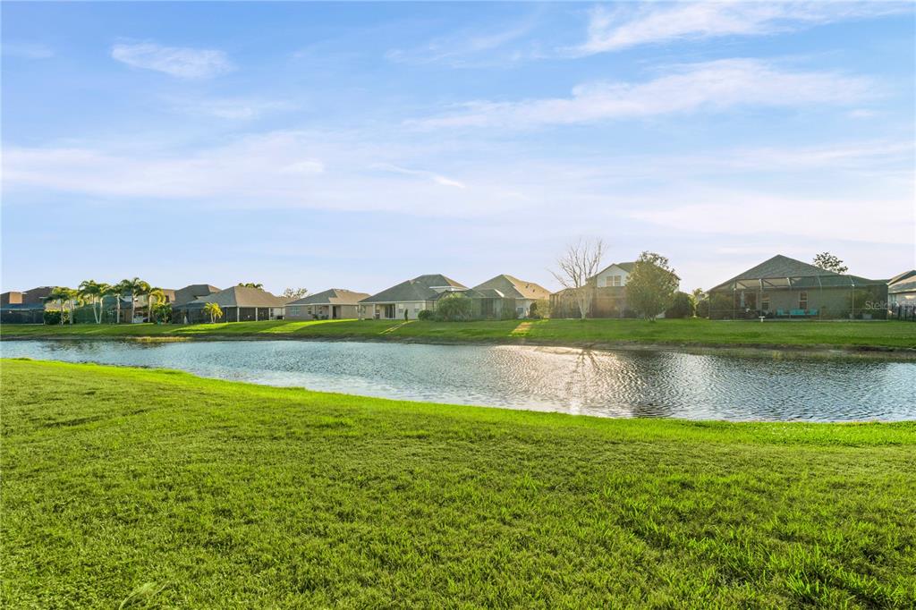 A view of a pond with several suburban houses in the background under a blue sky — 12807 24TH STREET CIRCLE E, PARRISH, FL