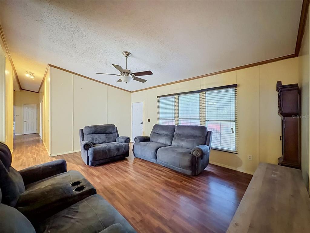 A living room features wood-look flooring, light-colored walls, a ceiling fan, and grey upholstered furniture — 14080 SE 122ND LANE ROAD, OCKLAWAHA, FL