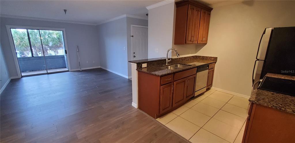 A kitchen with wood cabinets and granite countertops overlooks an open living area with flooring — 10263 GANDY BOULEVARD N UNIT 403, ST PETERSBURG, FL