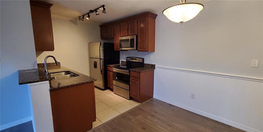 A kitchen features wood cabinets, granite countertops, stainless steel appliances, and a tile floor — 10263 GANDY BOULEVARD N UNIT 403, ST PETERSBURG, FL