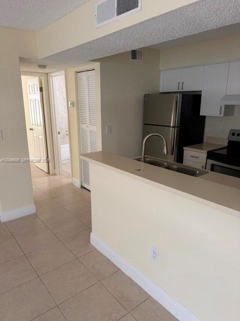 A kitchen with a breakfast bar, stainless steel refrigerator, and light-colored tile flooring — 1249 SW 46th Ave # 1401, Pompano Beach FL 33069, POMPANO BEACH, FL