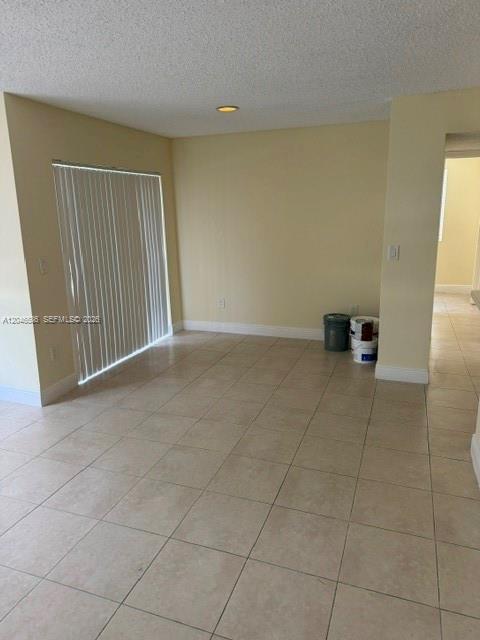 An empty room with beige tile flooring, light-colored walls, and a sliding glass door — 1249 SW 46th Ave # 1401, Pompano Beach FL 33069, POMPANO BEACH, FL