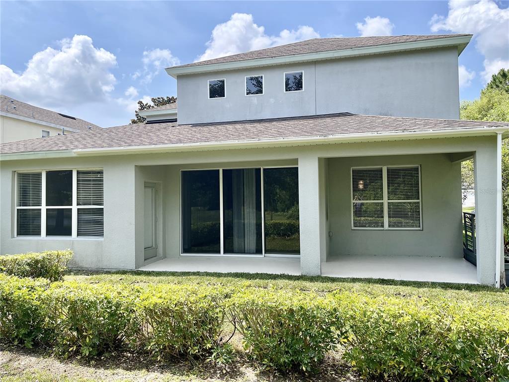 The exterior rear view of a two-story house features a covered patio and lawn — 8321 GREENBANK BOULEVARD, WINDERMERE, FL