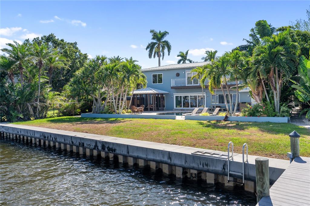 A two-story house with a pool and backyard sits along a concrete seawall and canal — 1710 POINT PLEASANT AVENUE W, BRADENTON, FL