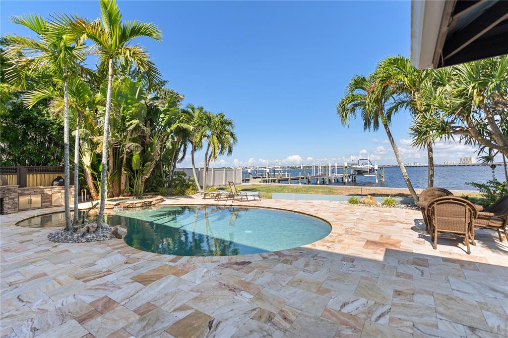 A backyard patio features a swimming pool, palm trees, and a view of the water — 1710 POINT PLEASANT AVENUE W, BRADENTON, FL