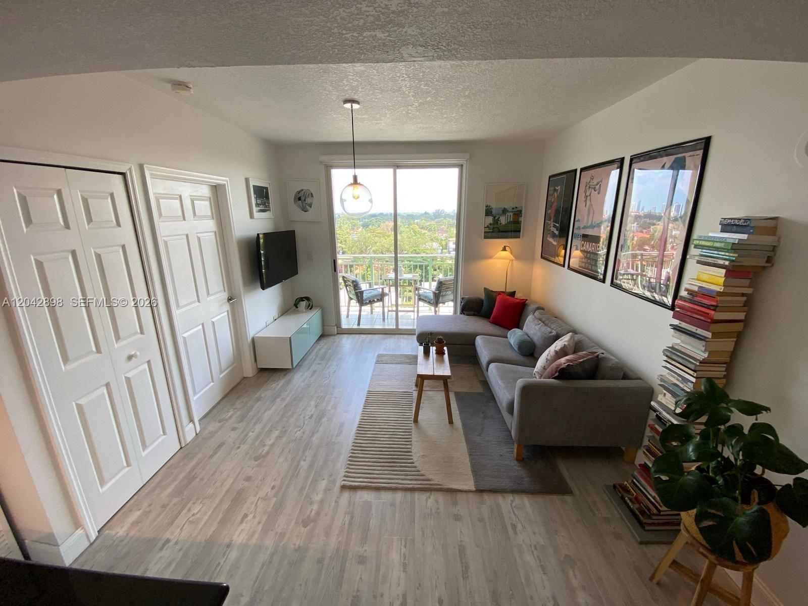 A living room features a gray sectional sofa, a tall bookshelf, and a balcony view — 3500 Coral Way # 707, Miami FL 33145, MIAMI, FL