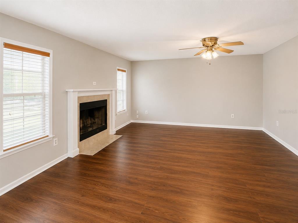 A living room features wood-look flooring, a fireplace, and a ceiling fan — 4104 QUAIL NEST COURT, ST CLOUD, FL
