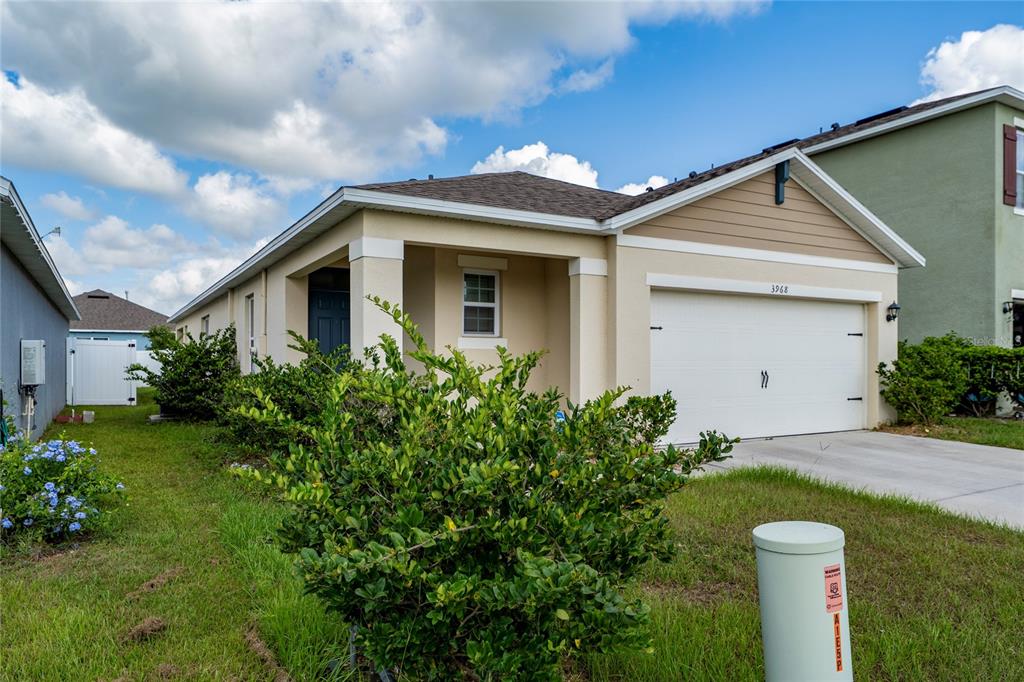 A single-story house with a white garage door, tan siding, and a small front yard — 3968 GADWALL PLACE, LEESBURG, FL