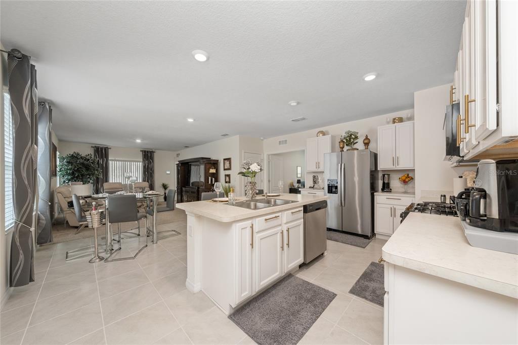 A kitchen with white cabinets and a center island opens into a dining area — 3968 GADWALL PLACE, LEESBURG, FL