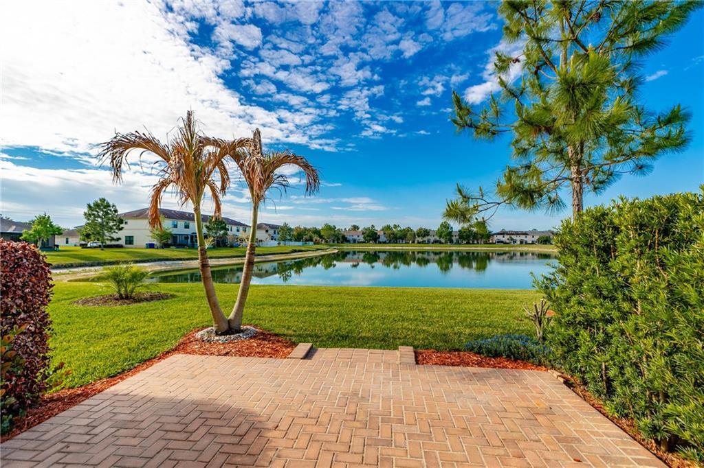 A brick patio overlooks a grassy lawn, a small pond, and residential buildings under a sky — VERO BEACH, FL