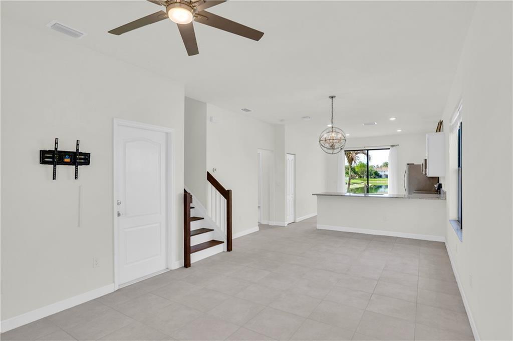 An open-concept living area with tile floors, a staircase, and a kitchen with a view — VERO BEACH, FL