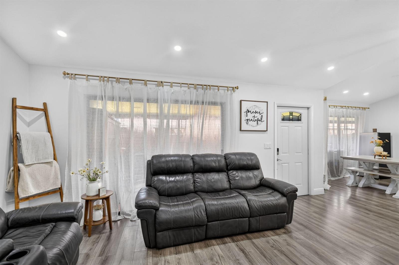 A living room features a dark leather sofa, wood-look flooring, and a white front door — 414 Springdale Circle, Palm Springs FL 33461, PALM SPRINGS, FL