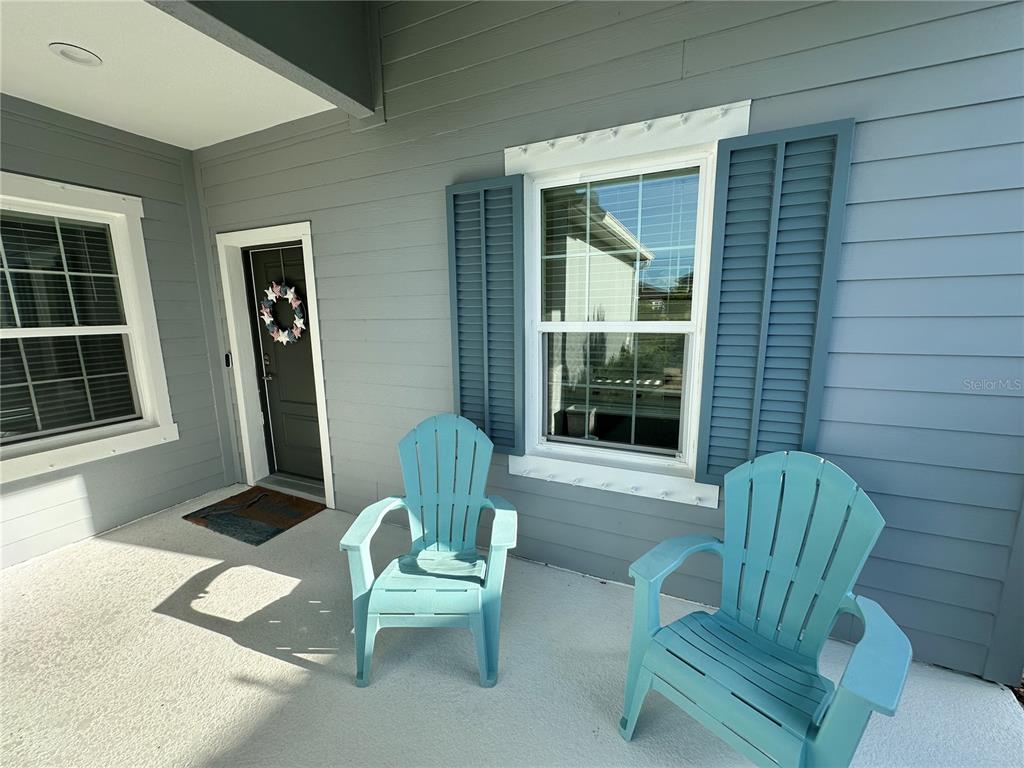 A covered porch features two light blue Adirondack chairs and a front door with a wreath — 4727 WILLOW BEND AVENUE, PARRISH, FL