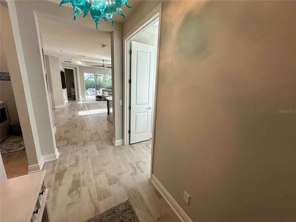 A hallway with light wood-look tile flooring leads toward an open living area — 4727 WILLOW BEND AVENUE, PARRISH, FL