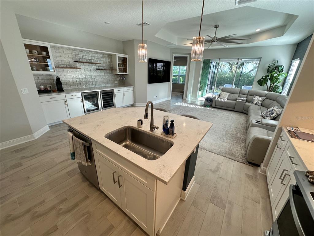 A kitchen with a central island and sink overlooks a living room with a sectional sofa — 4727 WILLOW BEND AVENUE, PARRISH, FL