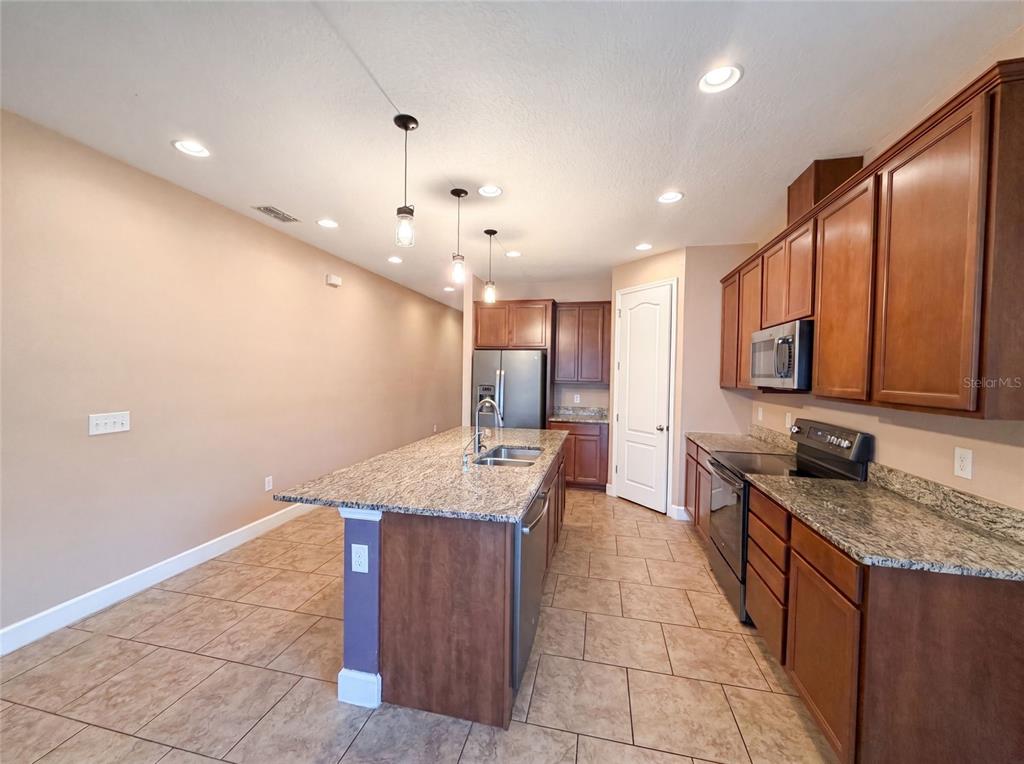 A kitchen features dark wood cabinets, granite countertops, a center island, and tile flooring — 480 BUCHANNAN DRIVE, DAVENPORT, FL