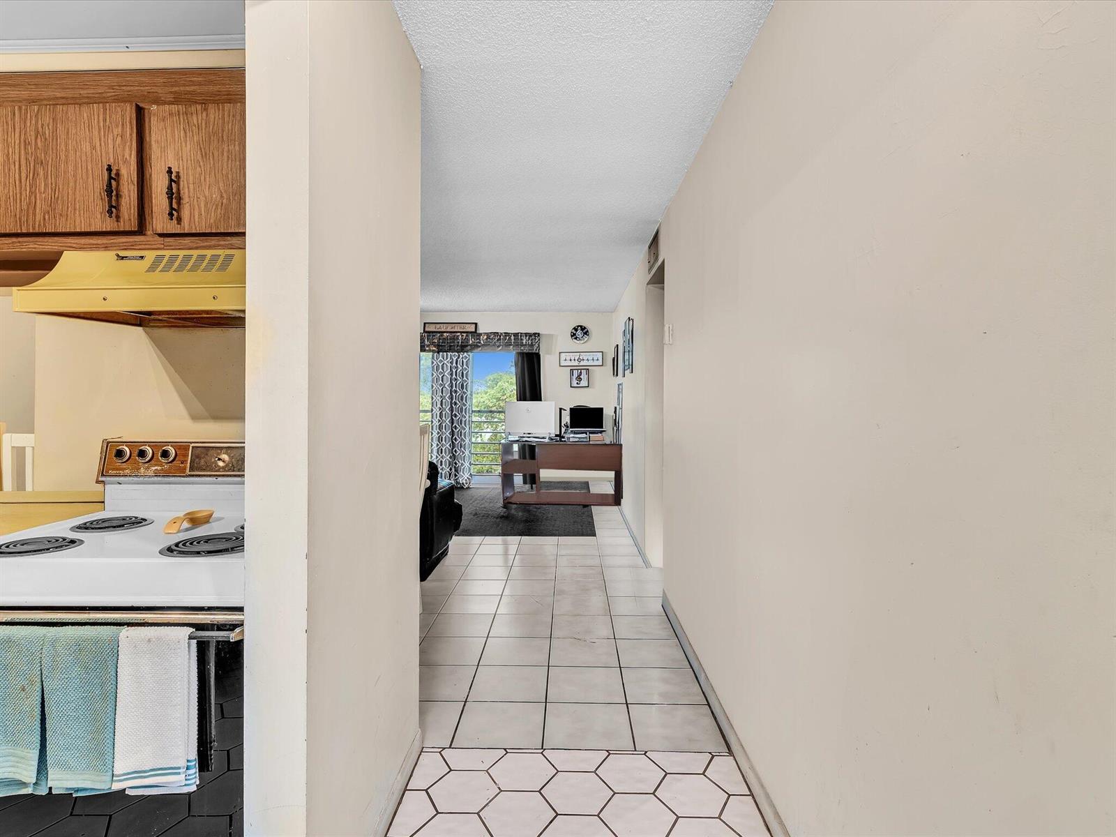 A view from a kitchen looking down a tiled hallway toward a living area — 2800 NW 56th # A404, Lauderhill FL 33313, LAUDERHILL, FL