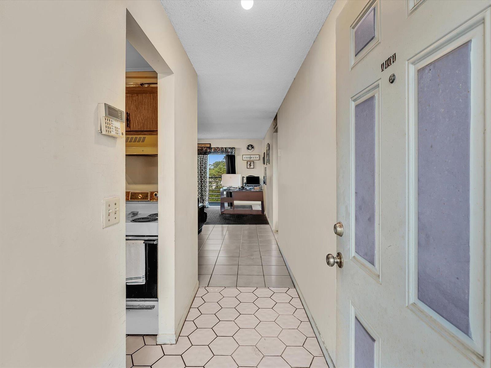 An entryway with hexagonal floor tiles leads to a kitchen and a living area beyond — 2800 NW 56th # A404, Lauderhill FL 33313, LAUDERHILL, FL