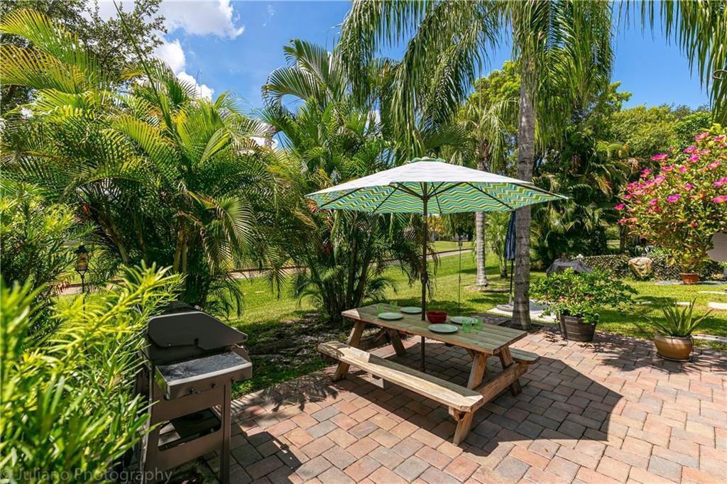 A brick patio features a wooden picnic table with an umbrella and a charcoal grill — 7610 Pinewalk Drive S # 128, Margate FL 33063, MARGATE, FL